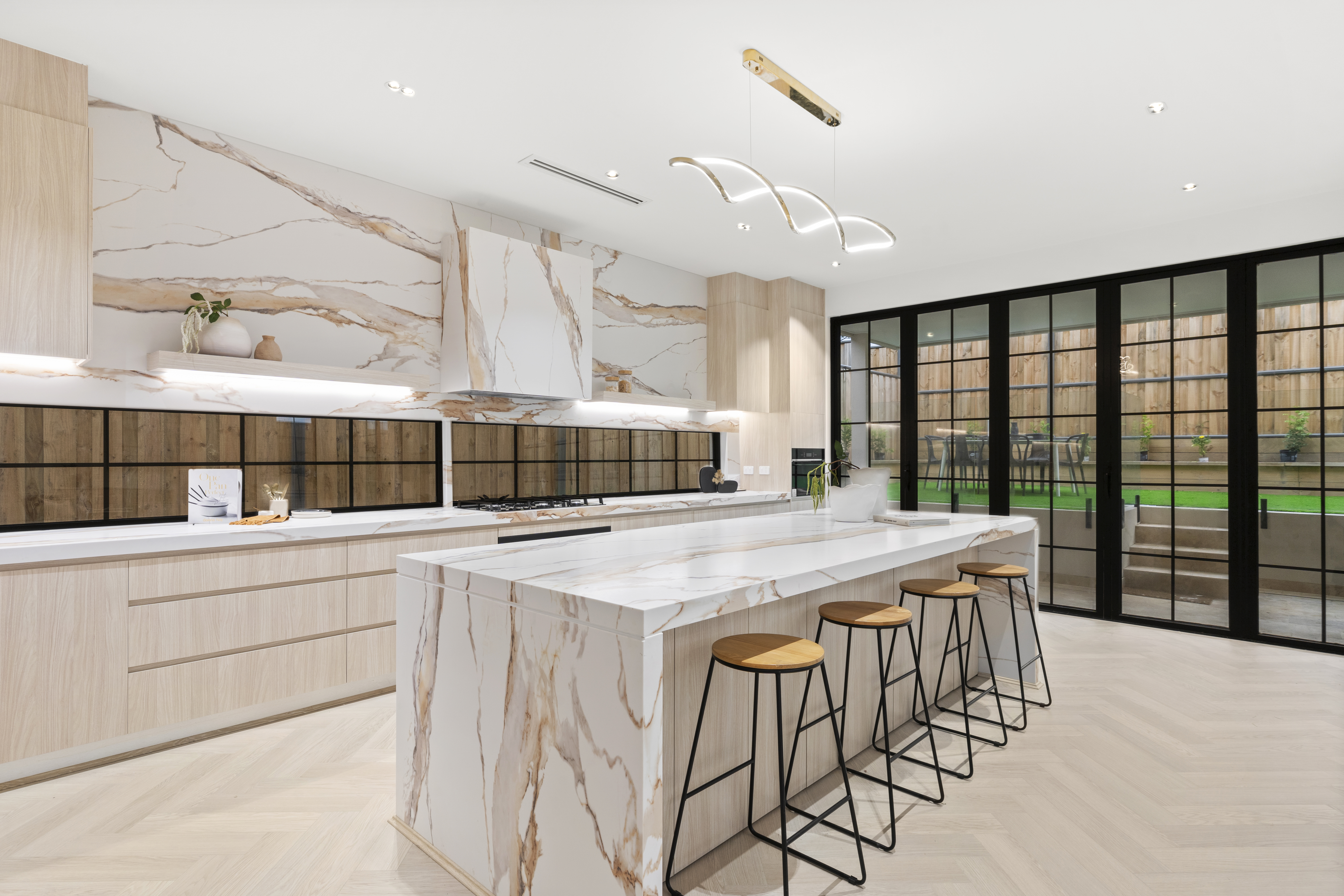 Calacatta marble kitchen with blonde timber and gold pendant lighting